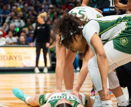 Storm players stand over their teammate after she was fouled onto the floor.