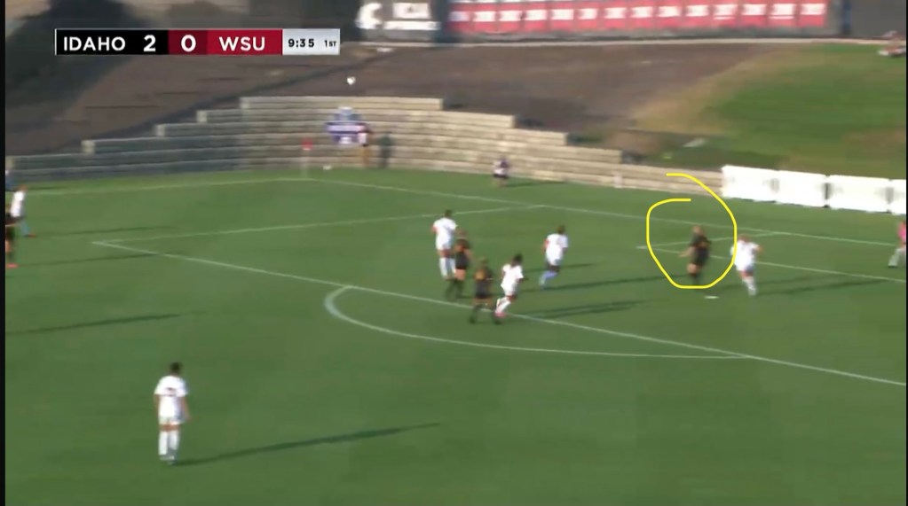 A soccer match in progress between Idaho and WSU, with Idaho leading 2-0. The scene shows players on the field, with one highlighted in a yellow circle.